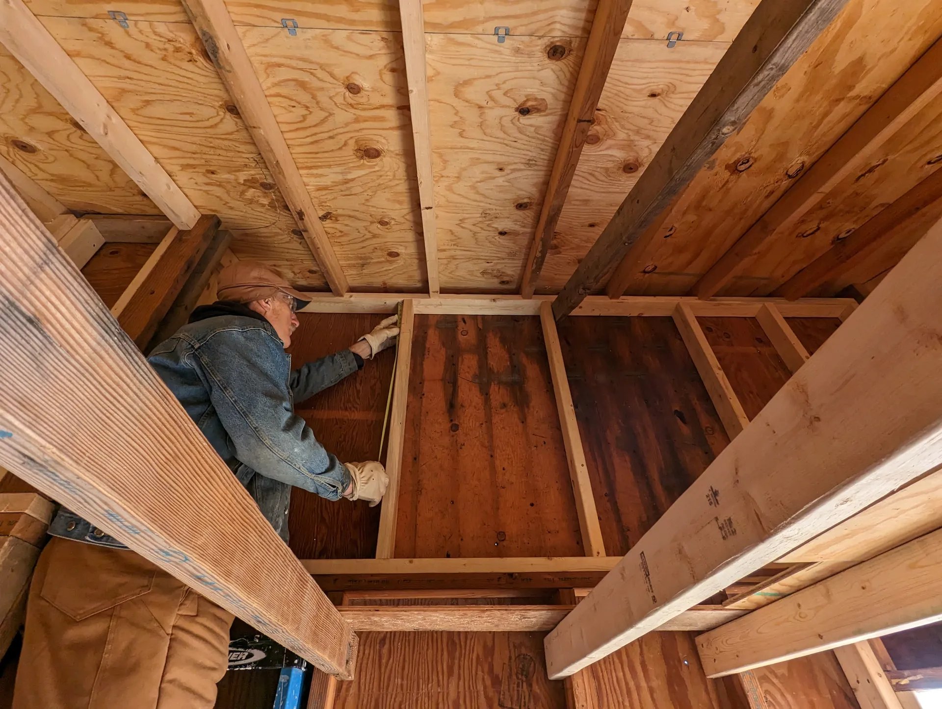 Dad measures the loft wall and considers methods for fitting the giant window