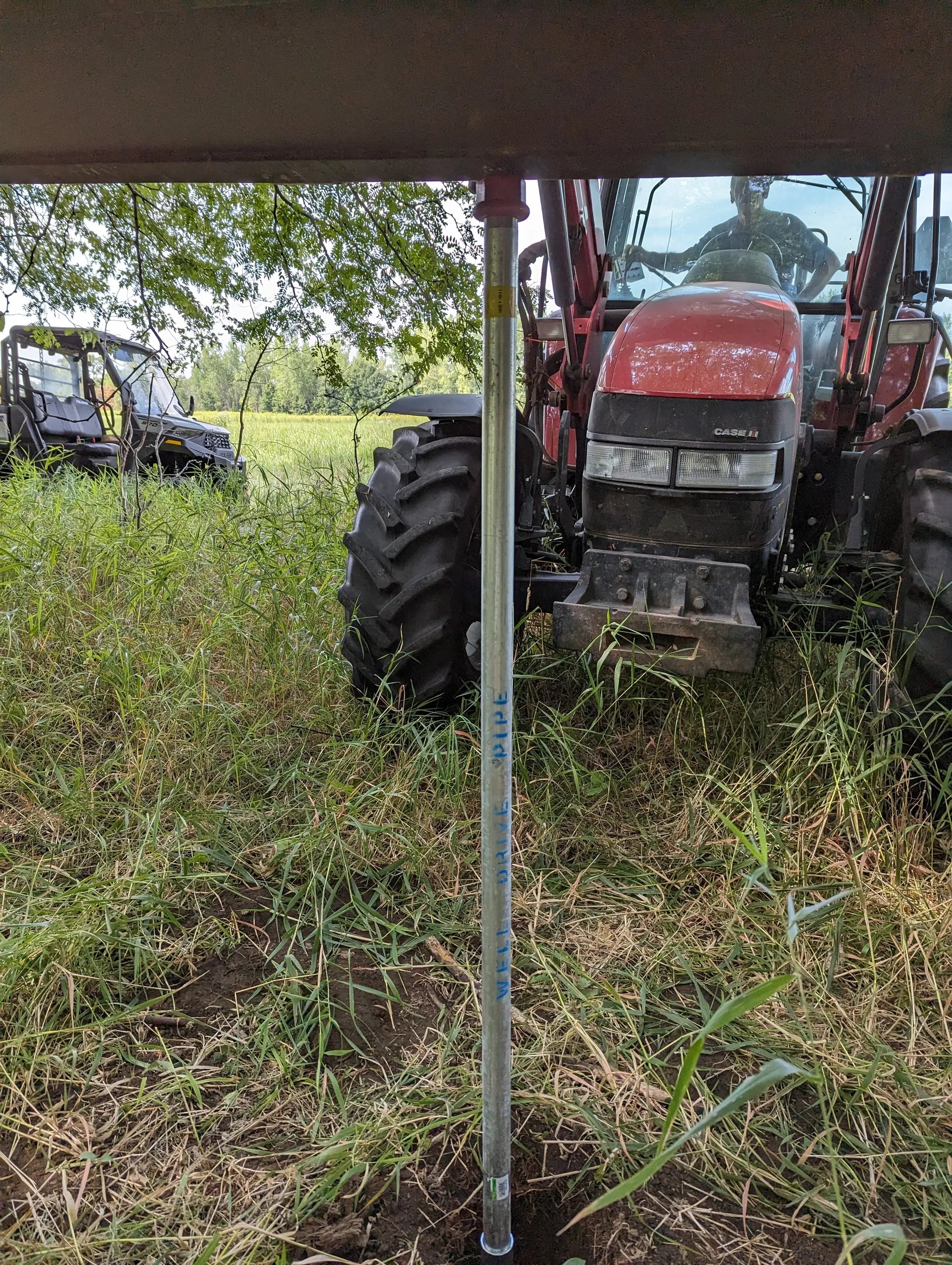 Using the tractor bucket to press the pipe into the ground