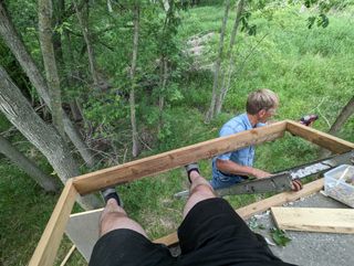 Holding up a 2x6 with my legs while dad runs the screw gun